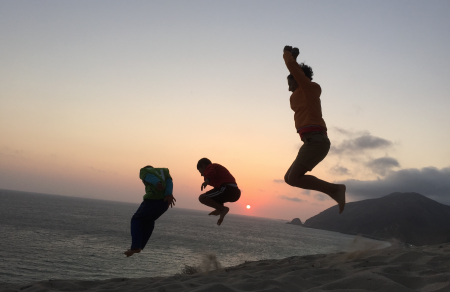 Some people jumping in the air on the sand